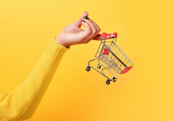 Frau hält einen Einkaufswagen an einem Finger